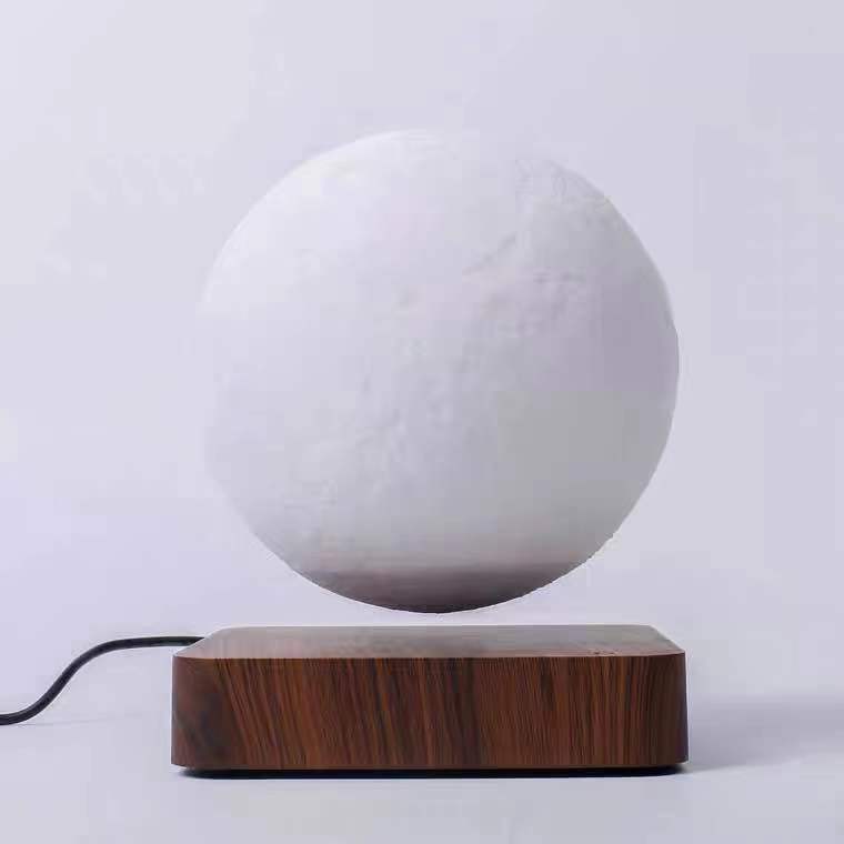 White spherical object levitating above a wooden base on a light gray background