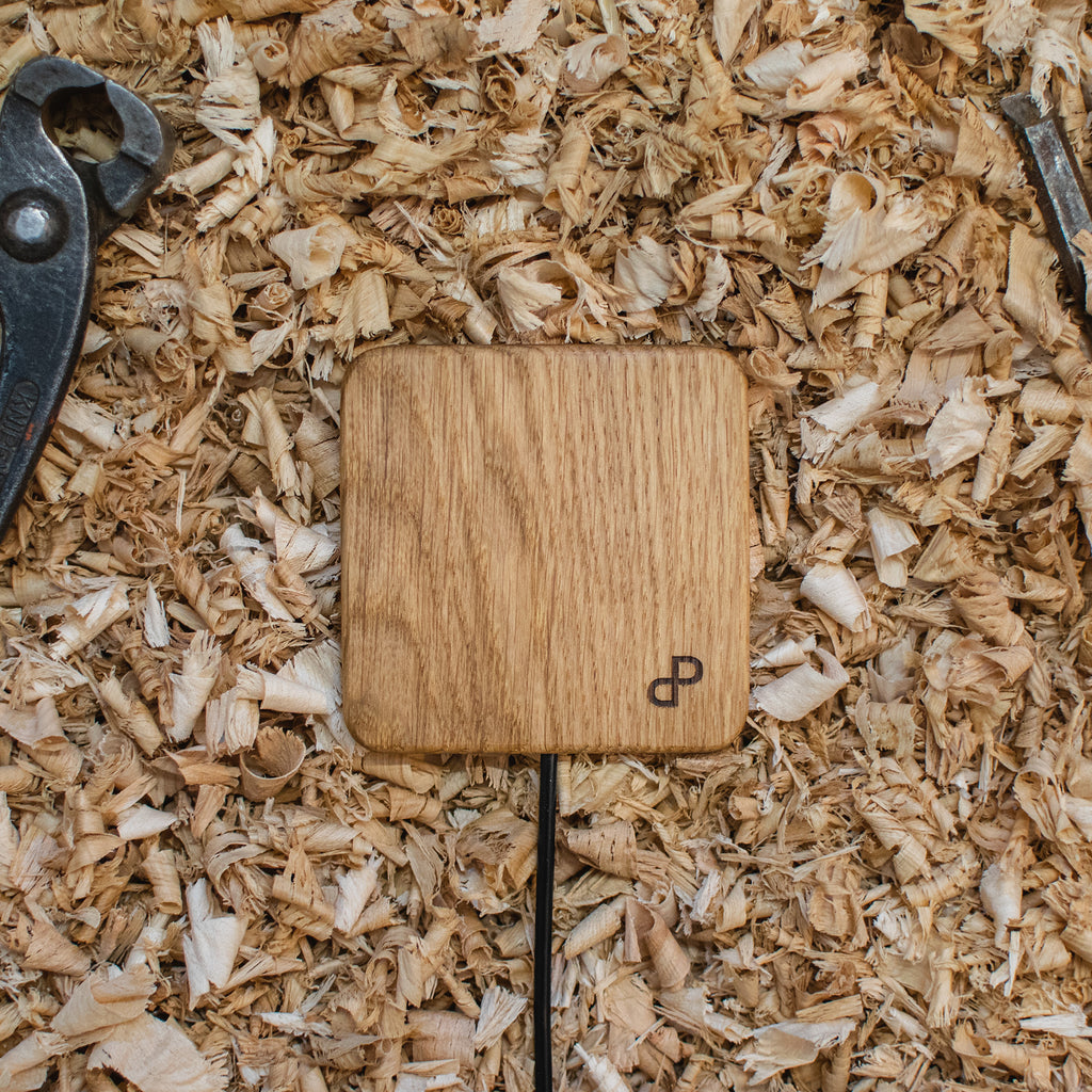 Wooden wireless charger with a brand logo on a bed of wood shavings