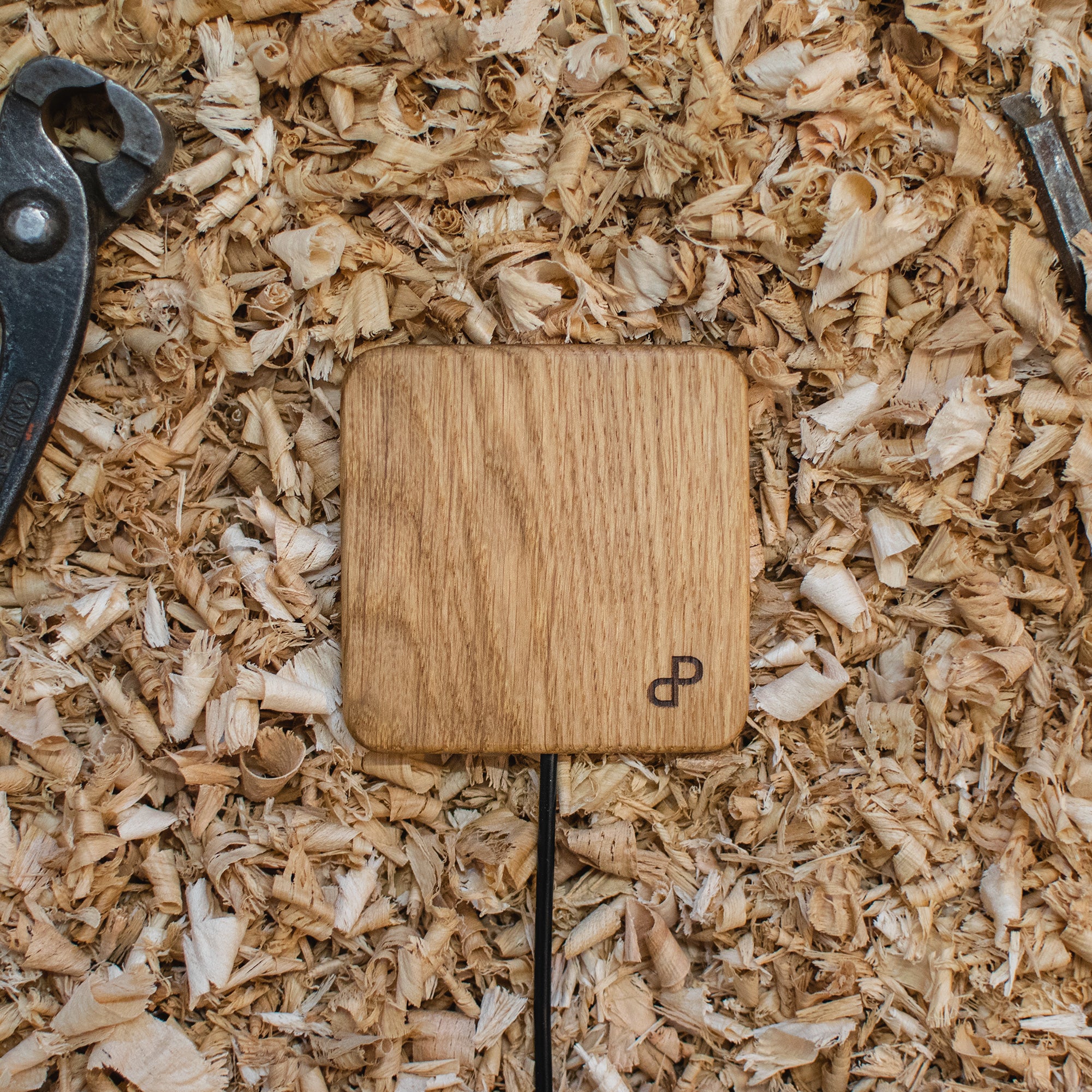 Wooden wireless charger with a brand logo on a bed of wood shavings
