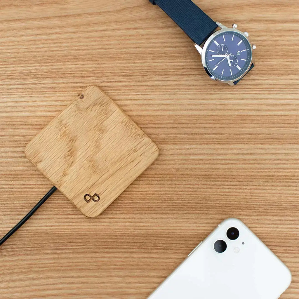 Wooden charging pad, smartphone, and watch on a wooden surface