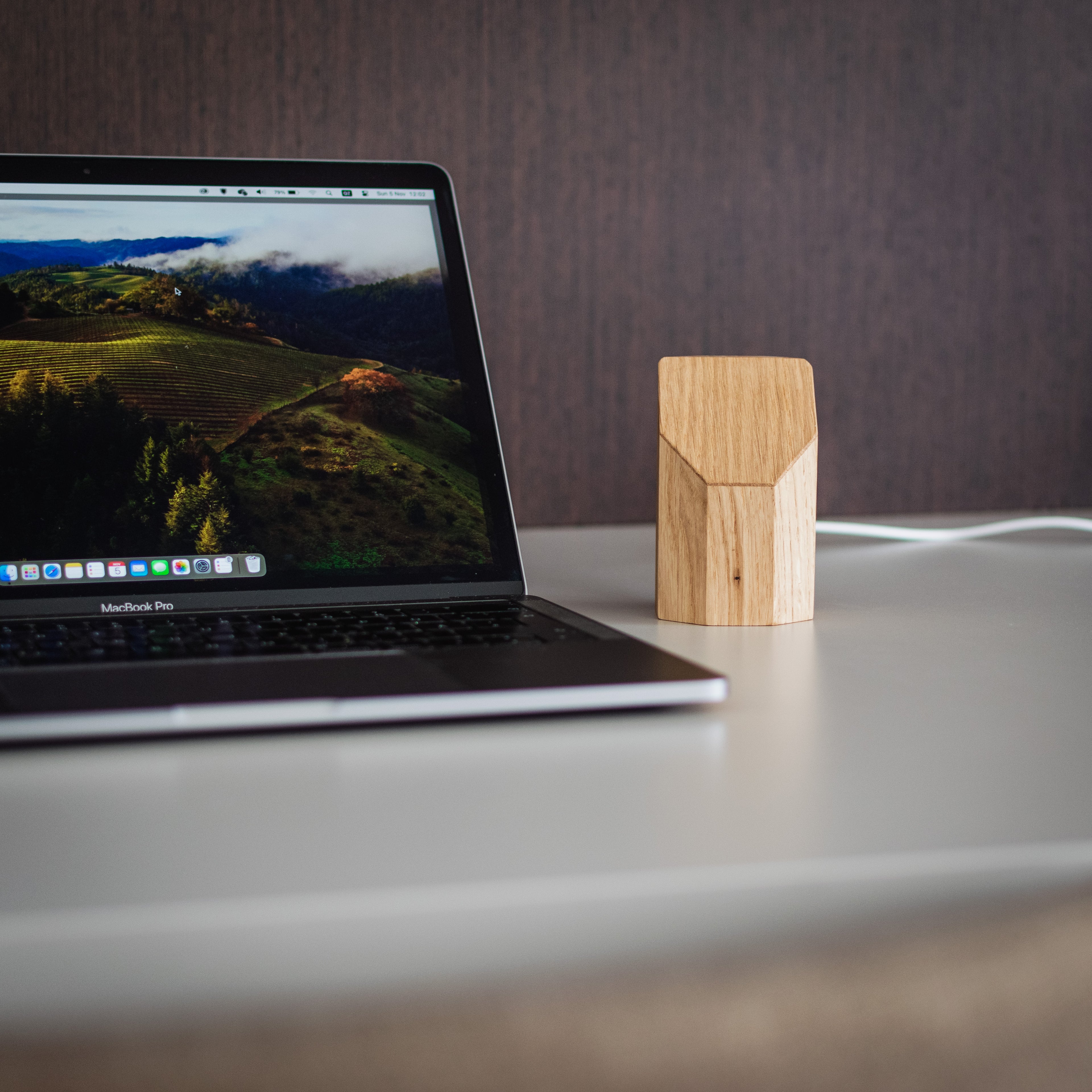 Laptop on a desk with a wooden device next to it