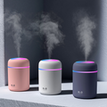 Three humidifiers emitting mist against a dark background.