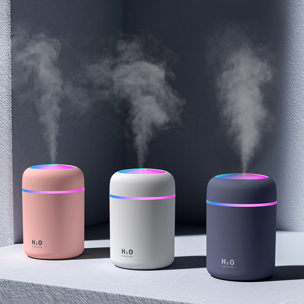 Three humidifiers emitting mist against a dark background.